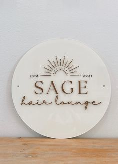 a sign that says sage hair lounge on the side of a wooden shelf in front of a white wall