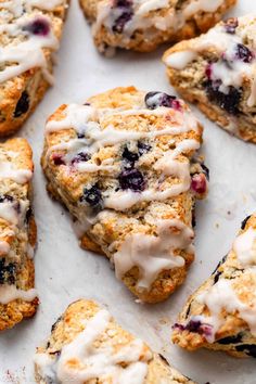 blueberry scones with white icing on a sheet of parchment paper, ready to be eaten