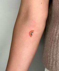 a woman's arm with a small rainbow tattoo on the left side of her arm