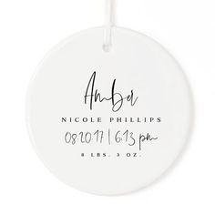 a white ceramic ornament with the names and date printed on it, hanging from a string