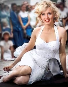 a woman in a white dress sitting on the ground