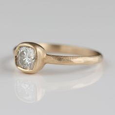 a yellow gold ring with a white diamond in the center, on a gray background