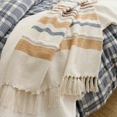 a blanket is folded on top of a bed with blue and white plaid sheets in the background