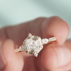 a person holding an engagement ring in their hand with three stones on each side and two diamonds on the other side