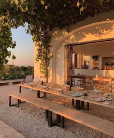 an outdoor dining area with wooden benches and tables set up for dinner on the patio