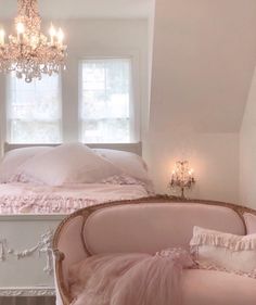 a bedroom with pink furniture and chandelier