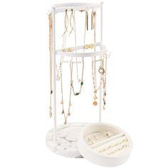 a white jewelry rack with multiple necklaces hanging from it's sides on a marble stand