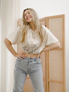 a woman with her hands on her hips posing for the camera while wearing jeans and a t - shirt