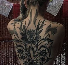 the back of a woman's body with tattoos on it