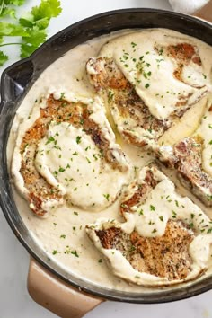 a skillet filled with meat covered in gravy and garnished with parsley