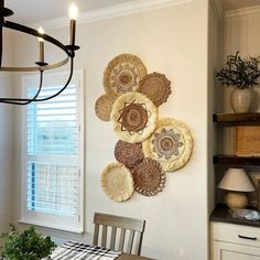 a dining room table and chairs in front of a wall hanging with plates on it