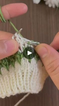 someone is crocheting the stitches on a white knitted object with green needles