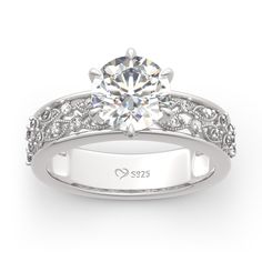 a white gold engagement ring with diamonds on the sides and an engraved band around it