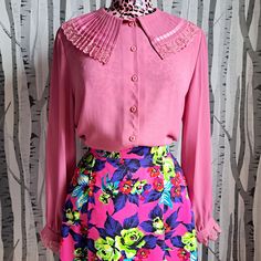 This 1970s dusky pink blouse with its sweet feminine tailoring details is a really wonderful garment. A great statement shirt is an absolute wardrobe essential and can elevate so many outfits.  The neckline is a theatrical pleated, frill collar edged in pink lace. The sleeves are loose and flowing with buttoned cuffs edged in machting lace frills.  It's in fantastic vintage condition with no stains, tears or repairs. One or two very minor pulls but nothing major.  Best fit is a modern UK size 14 Pink Long Sleeve Blouse With Lace Collar, Pink Tops With Ruffles And Collar, Fitted Workwear Blouse With Cute Collar, Fitted Blouse With Cute Collar For Work, Chic Pink Blouse With Lace Trim, Pink Lace Collar Top For Spring, Fitted Pink Blouse With Lace Collar, Spring Pink Top With Lace Collar, Pink Ruffled Top With Peter Pan Collar