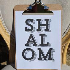 a clipboard with the words shl alom on it attached to a chair