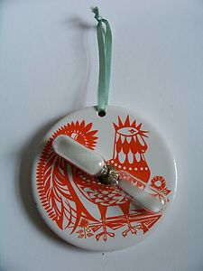 an orange and white ornament hanging from a green cord on a white surface