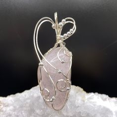 This beautiful rose quartz stone is a soft pink color with an iridescent glow coming from within the specimen. The stone is semi-transparent, so the internal crystalline structure is visible. The cool tone of the soft pink color is accented with silver plated anti-tarnish wire and beads. The graceful design of the wrapping brings out the beauty of the stone.  Ancient customs and lore indicate that gemstones can bring peace, health, protection and spiritual favor. There is a belief that rose quartz has calming effects and helps people develop strong friendships.  It is considered a stone representing love and compassion.    The pendant measures 3 inches high by 1 inch wide by 3/4 inch front to back.  The bale opening measures 1/3 inches high by 1/2 inches wide.    A complimentary faux suede Elegant Pink Jewelry Hand Wrapped, Elegant Hand Wrapped Pink Jewelry, Elegant Pink Hand Wrapped Jewelry, Pink Quartz Jewelry Gift, Pink Quartz Jewelry As Gift, Pink Quartz Jewelry For Gift, Pink Quartz Jewelry As A Gift, Pink Quartz Jewelry For Gifts, Pink Rose Quartz Hand Wrapped Jewelry