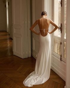 a woman in a white dress looking out the window