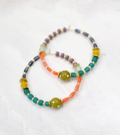 two beaded bracelets with beads on white background, one is green and the other is orange