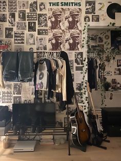 a room with guitars, clothes and posters on the wall