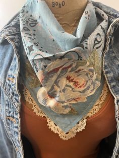 a mannequin wearing a blue jean jacket with a floral scarf on it's neck