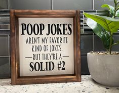 a potted plant sitting next to a sign that says poop jokes aren't my favorite kind of jokes, but they're sold 2