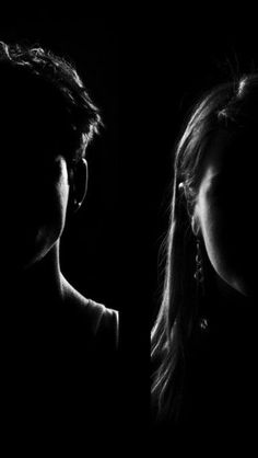 two people standing in the dark with their faces close together