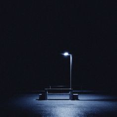 an empty parking lot at night with a street light in the dark and no one around it