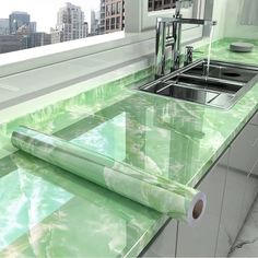 a kitchen counter with green marble on it and a roll of toilet paper in front of the sink