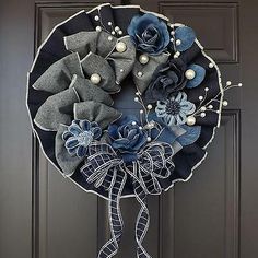 a wreath with blue flowers and pearls hanging on the front door's black door