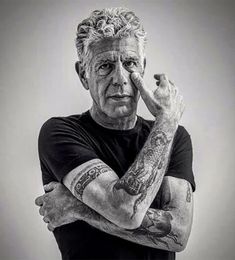 an older man with tattoos on his arm and arms, posing for a black and white photo