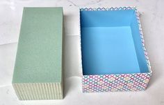 an empty box with a blue lid next to a smaller box that has a pattern on it