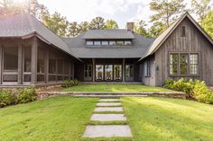 a large house with stone steps leading to the front door and entry way, surrounded by lush green grass