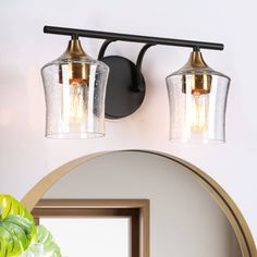 two light bathroom fixture with clear glass shades on the wall and mirror in front of it