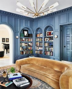 a living room filled with furniture and bookshelves next to a piano in the corner