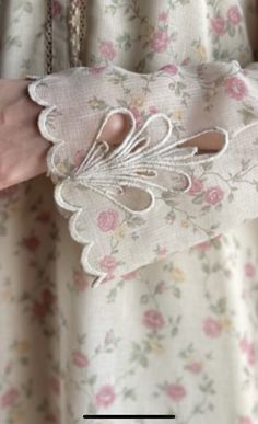 a close up of a person's hand holding a piece of cloth with flowers on it