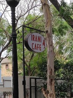 a sign for an italian cafe hanging from a lamp post in front of a fence