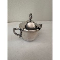 a silver sauce pot on a white table