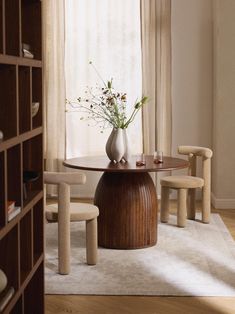 a vase with flowers is sitting on a table in front of a book shelf filled with books