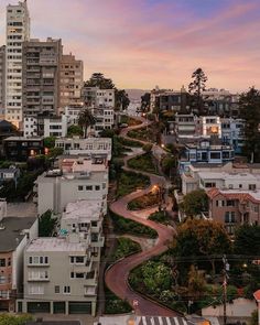 an aerial view of a city with many buildings and trees in the foreground at sunset