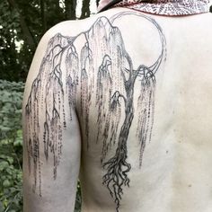 the back of a man's body with trees and mountains tattooed on his back