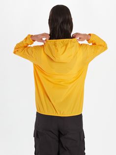 the back of a woman's yellow jacket with her hands on her hips,