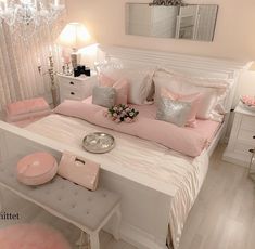 a white bed topped with lots of pillows and pink blankets next to a table filled with flowers