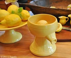 two yellow dishes with lemons in them on a wooden table next to a cutting board