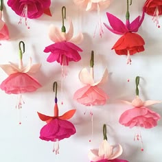 pink and red paper flowers hanging from hooks