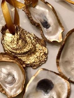 four oysters with gold foil on them and a ribbon tied around the edges, sitting on a white surface