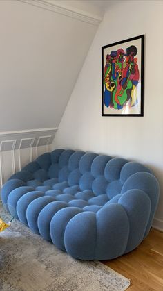 a blue couch sitting on top of a hard wood floor next to a white wall