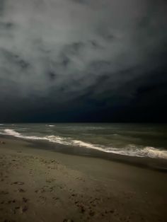 the sky is dark and cloudy over the beach