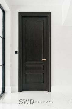 an empty room with a black door and white walls