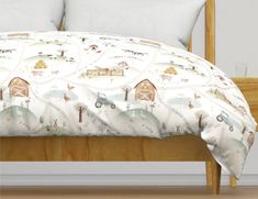 a bed covered in a white comforter with farm animals and trees on the cover